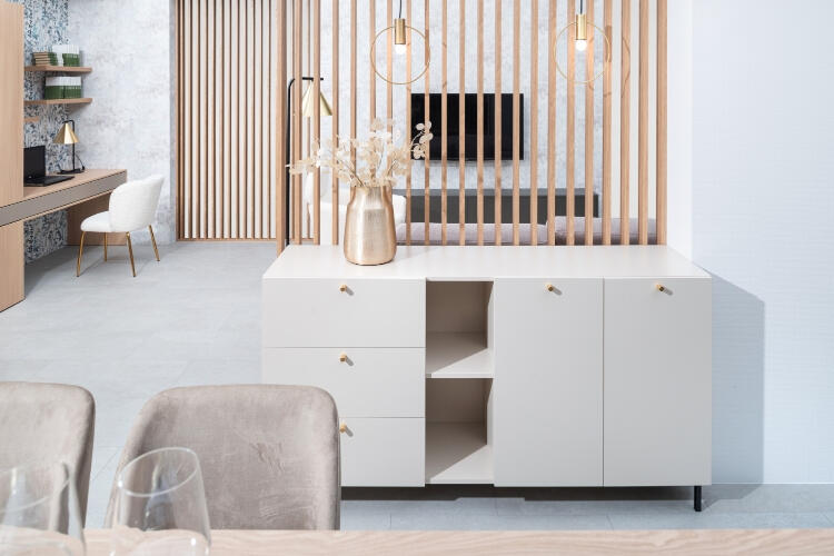 Decodom prispôsobiteľný úložný nábytok v pastelovej odtiene, zdôraznený zlatými detailmi a moderným dreveným obkladom. Minimalistická Decodom komoda na mieru s elegantnými zlatými úchytmi a otvorenými policami.